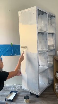 a man painting a white cabinet in a room