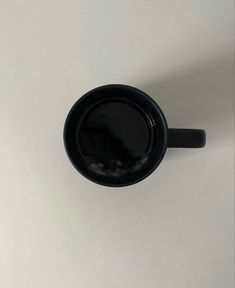 a black coffee cup sitting on top of a white table