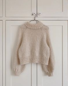 a sweater hanging on a hook in front of white cupboards