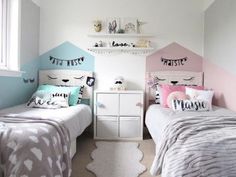 two beds in a room with white walls and pink and blue decor on the headboards