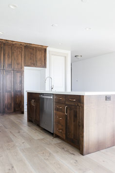 an empty kitchen with wooden cabinets and stainless steel dishwasher in the center island