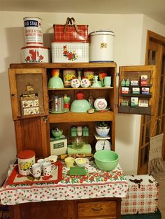 an old fashioned kitchen with many items on the shelves and dishes in front of it