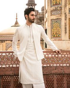 a man standing in front of a building wearing a white outfit