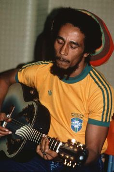 a man with dreadlocks playing an acoustic guitar