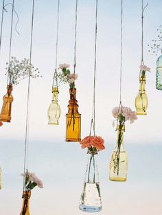 hanging glass bottles with flowers in them are suspended from the ceiling by strings and string