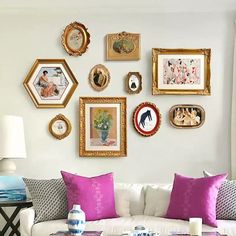 a living room filled with lots of framed pictures on the wall above a white couch