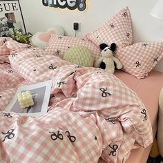 a bed covered in pink and white checkered sheets with a teddy bear on it