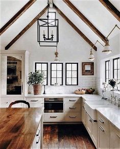 a kitchen with white cabinets and wooden floors is pictured in this image, the ceiling has exposed beams