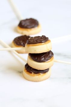 chocolate covered donuts are stacked on top of each other with toothpicks in the background