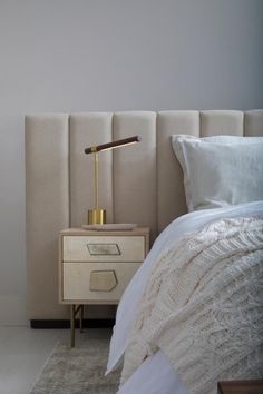 a white bed sitting next to a night stand with a lamp on top of it