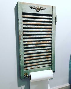 an old wooden shutter mounted to the side of a wall next to a roll of toilet paper