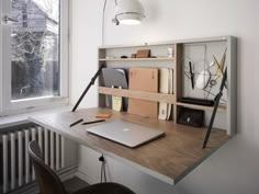 a laptop computer sitting on top of a wooden desk next to a radiator