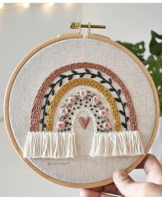 someone is holding up a small embroidery hoop with a rainbow in the middle and flowers on it