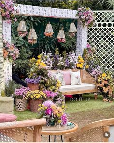 an outdoor seating area with wicker furniture and flowers on the grass in front of it