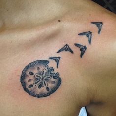 a tattoo on the back of a man's shoulder with birds flying around it