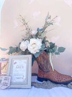 a cowboy boot with flowers in it next to a photo frame