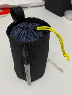 a small black bag sitting on top of a white table next to a pair of scissors