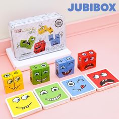 an assortment of colorful cubes with faces on them sitting in front of a box