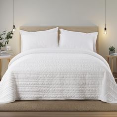 the bed is made with white linens and pillows, along with two side tables