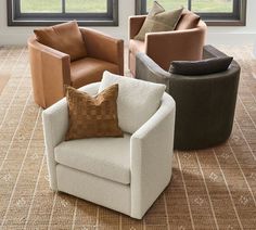 four different colored chairs sitting in front of large windows on carpeted floor with rug