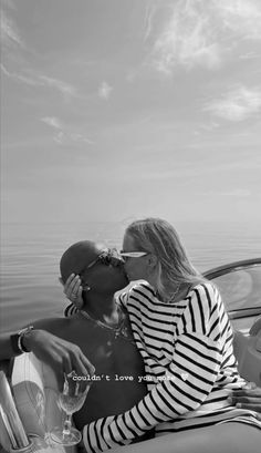 black and white photo of two people kissing in a boat on the water with sky background