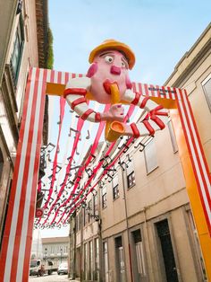 a pink stuffed animal hanging from the side of a building next to red and white striped poles