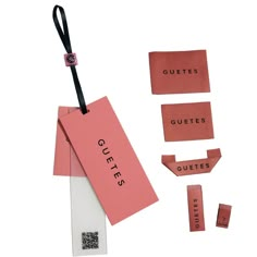 pink tags with black letters on them and some clips attached to the back of each tag