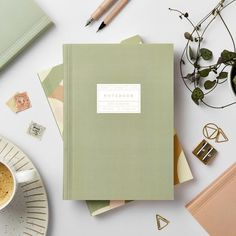 an open notebook sitting on top of a table next to a cup of coffee and other office supplies