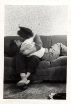 an old black and white photo of two children on a couch with their arms around each other