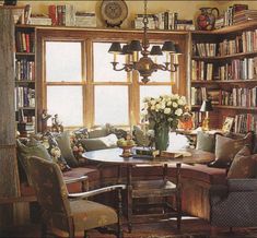 a living room filled with lots of furniture and bookshelves next to a window