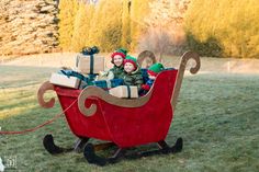 two children are riding in a sleigh with presents