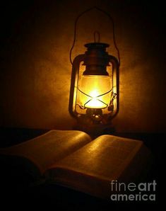 an open book sitting on top of a table next to a light bulb in the dark