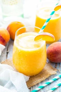 two glasses filled with orange juice next to peaches