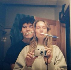 two people taking a selfie in front of a mirror with toothbrushes sticking out of their mouths