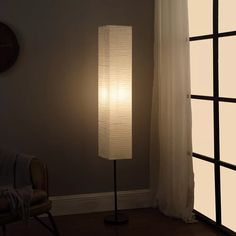 a lamp that is next to a window in a room with a chair and rug