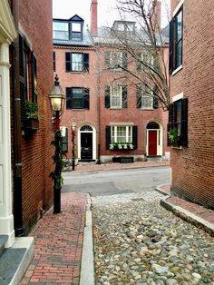 an alley way with brick buildings and cobblestone walkway leading to the front door