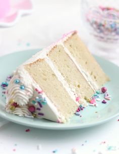 a slice of cake with white frosting and sprinkles on a plate