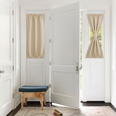 an open door in a white room with a blue bench and rug on the floor