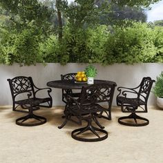 an outdoor table and chairs with fruit on the table in front of a planter