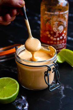 a spoon full of spicy mayo sauce on top of a table with limes and other ingredients