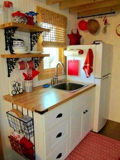 a kitchen with a sink, refrigerator and shelves on the wall above it's counter