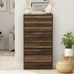 a wooden chest of drawers sitting next to a potted plant in a living room