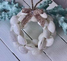 a wreath made out of seashells on top of a white wooden table next to some branches