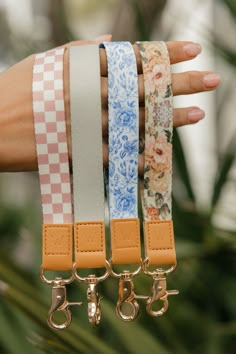 a person holding four different colored bracelets in their hand with flowers on the straps