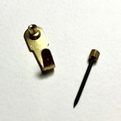 a small metal object sitting on top of a piece of paper next to a screw