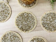 four white beaded coasters sitting on top of a wooden table