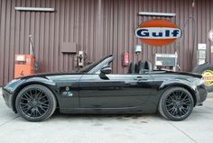 a black sports car parked in front of a gulf gas station