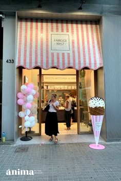 a woman standing in front of a pink and white striped store