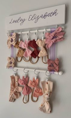 there are many small bows hanging on the hooks in this wall rack that is attached to the wall