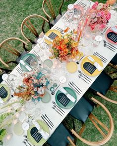 a long table is set with plates, flowers and candles for an outdoor dinner party